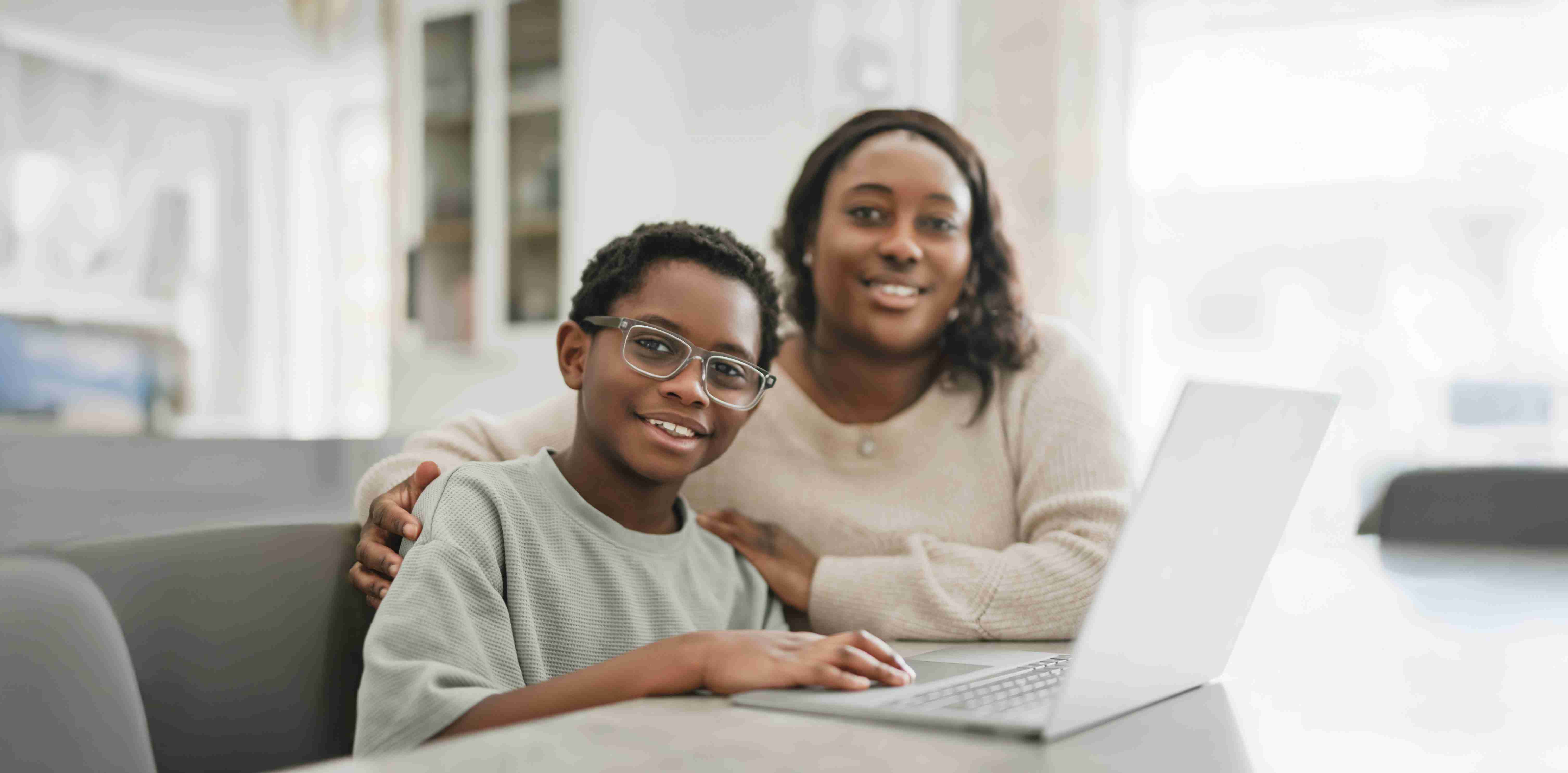 Mother and her son working together at home with their laptop
